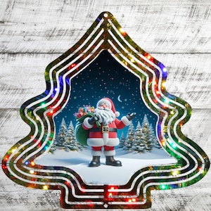 May include: A metal Christmas tree wind chime with a colorful, swirling design. The chime features a festive image of Santa Claus carrying a bag of gifts in a snowy winter scene. The tree is decorated with multi-colored LED lights.