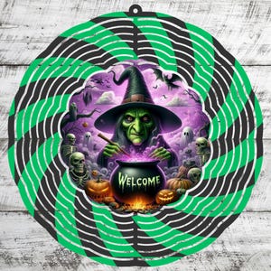May include: A Halloween-themed wind spinner featuring a green-skinned witch stirring a bubbling cauldron with the word "WELCOME". The design includes pumpkins, ghosts, and skeletons, surrounded by a green and black spiral pattern.