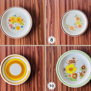 May include: Four vintage ceramic plates with floral designs. Each plate features a different pattern of flowers in shades of yellow, orange, and blue, with brown or green rims. The plates are set against a wooden background.