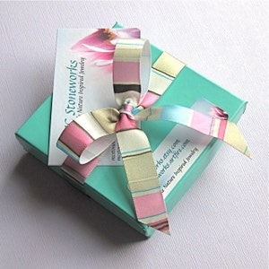 May include: A turquoise gift box with a pink and white striped ribbon tied in a bow. The box has a white card attached to it with the text "Stoneworks - Nature Inspired Jewelry" and the website address "works.etsy.com works.artfire.com".