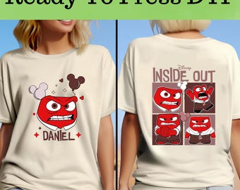 Op de afbeelding: Crèmekleurig T-shirt met een afbeelding van het personage Woede uit de Disney Pixar-film Inside Out. De voorkant van het shirt heeft Woedes gezicht met de naam "DANIEL" eronder. De achterkant van het shirt heeft een ontwerp met vier panelen met Woede.