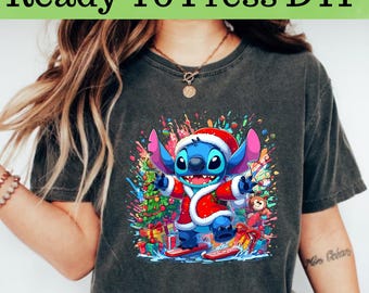 May include: A dark gray t-shirt with a colorful graphic of a blue Stitch character wearing a Santa hat and holding a Christmas tree. The graphic is surrounded by colorful paint splatters.