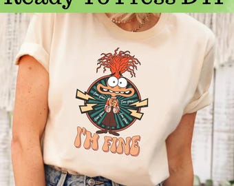Op de afbeelding: Crèmekleurig T-shirt met een cartoonafbeelding van een personage met oranje haar en een bezorgde uitdrukking. De afbeelding staat in een cirkel met bliksemschichten en de woorden "I'm Fine". De tekst "Ready To Press DTF" staat bovenaan.