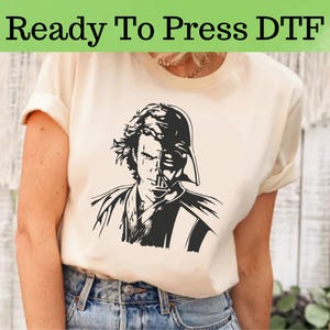May include: A white t-shirt with a black and white graphic of Darth Vader and Anakin Skywalker. The graphic shows Darth Vader's helmet over Anakin's face. The text "Ready To Press DTF" is at the top of the image.