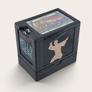 Könnte beinhalten: Eine schwarze, rechteckige Deck-Box mit strukturierter Oberfläche, hellblauem 'HELLO THERE'-Schriftzug an der Seite und einer beigen Silhouette einer Figur mit Lichtschwert auf der Vorderseite. Eine Spielkarte ist im oberen Schlitz sichtbar.