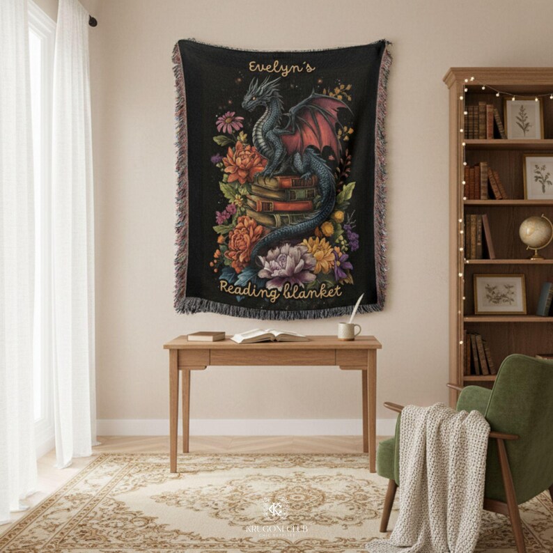 May include: A black woven throw blanket featuring a central illustration of a dragon perched on a stack of books surrounded by colorful flowers. The text "Evelyn's Reading blanket" is printed in gold script at the top and bottom of the design.