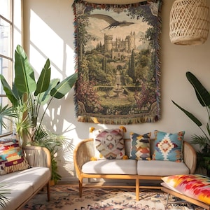 Pode incluir: Uma tape&ccedil;aria de parede retangular tecida apresentando uma cena de paisagem detalhada com um grande castelo de pedra, uma fonte central, vegeta&ccedil;&atilde;o exuberante e um drag&atilde;o voador. A tape&ccedil;aria tem uma borda com franjas de fios multicoloridos.