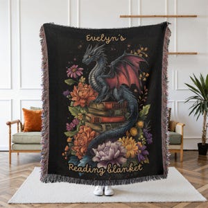 Personalized dragon reading woven blanket with custom name, fantasy dragon on stacked books, colorful floral details, dark gothic background, and bookish reading nook design.
