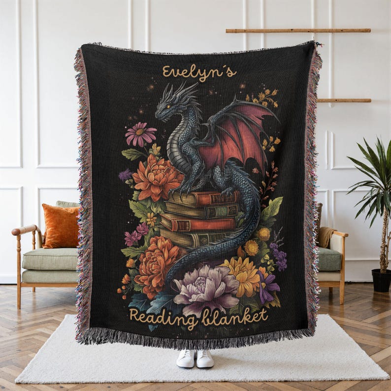 Personalized dragon reading woven blanket with custom name, fantasy dragon on stacked books, colorful floral details, dark gothic background, and bookish reading nook design.