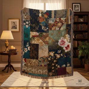 May include: A patchwork throw blanket with a floral design in shades of navy, teal, and beige. The blanket features a fringed edge and a variety of floral patterns, including large pink and white flowers. The overall aesthetic is vintage and decorative.