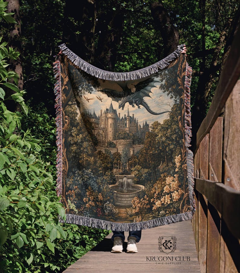 May include: A tapestry throw blanket featuring a fantasy castle scene with a dragon in flight. The blanket has a detailed illustration with a castle, trees, and a fountain. The edges are finished with fringe.