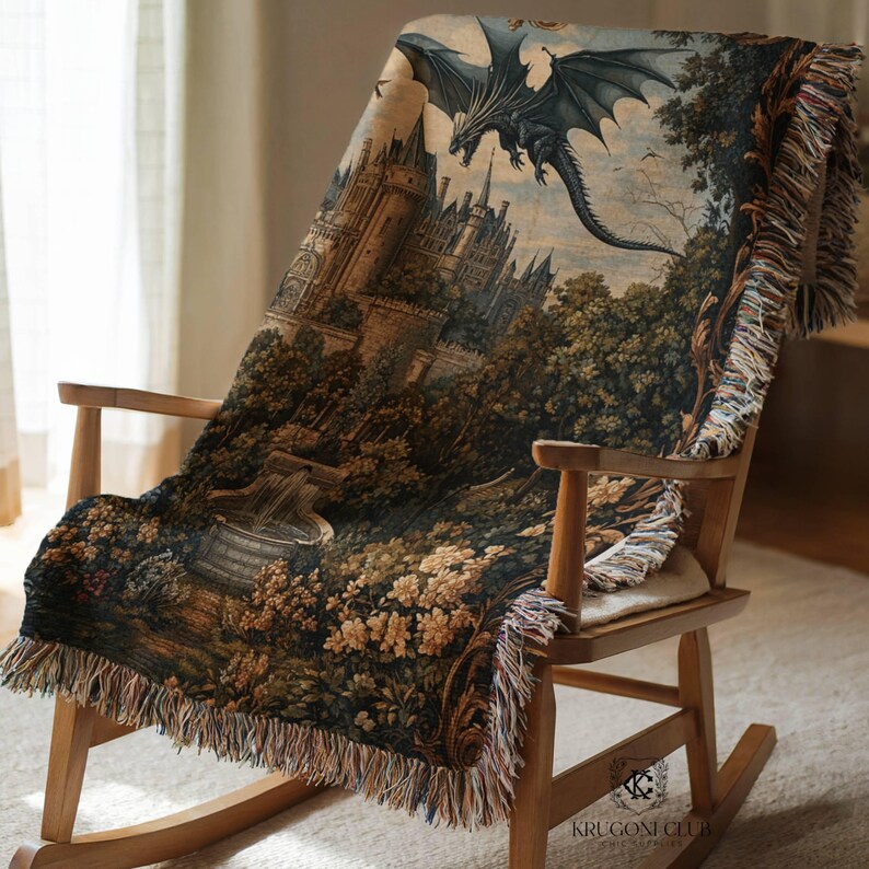 May include: A woven throw blanket draped over a wooden rocking chair. The blanket features a detailed fantasy scene with a castle, trees, and a flying dragon in shades of brown, green, and blue. The edges have a fringed trim.