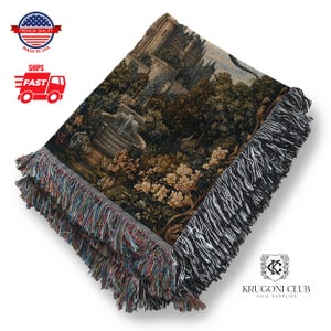May include: Woven tapestry throw blanket with a detailed landscape scene featuring a fountain, trees, and a castle. The blanket has a fringed edge with multiple colors. The words "Premium Quality" and "Made in USA" are visible.