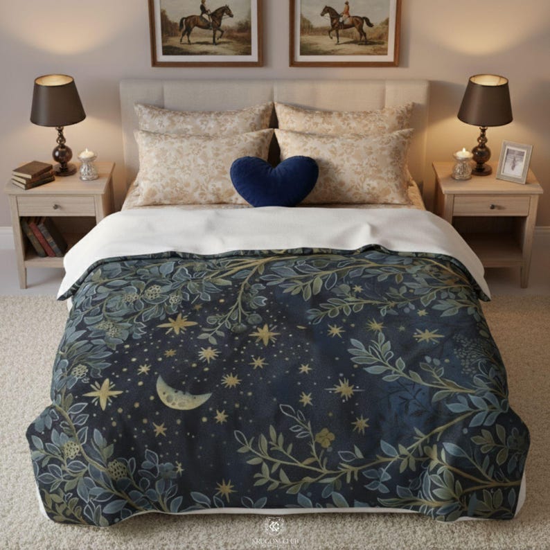 Celestial moon and stars fleece minky blanket displayed on elegant bedroom bed with white linens and navy blue heart pillow, featuring botanical sage green foliage border surrounding crescent moon and golden stars on dark navy background, creating cozy witchy boho bedroom decor perfect for mystical home aesthetics