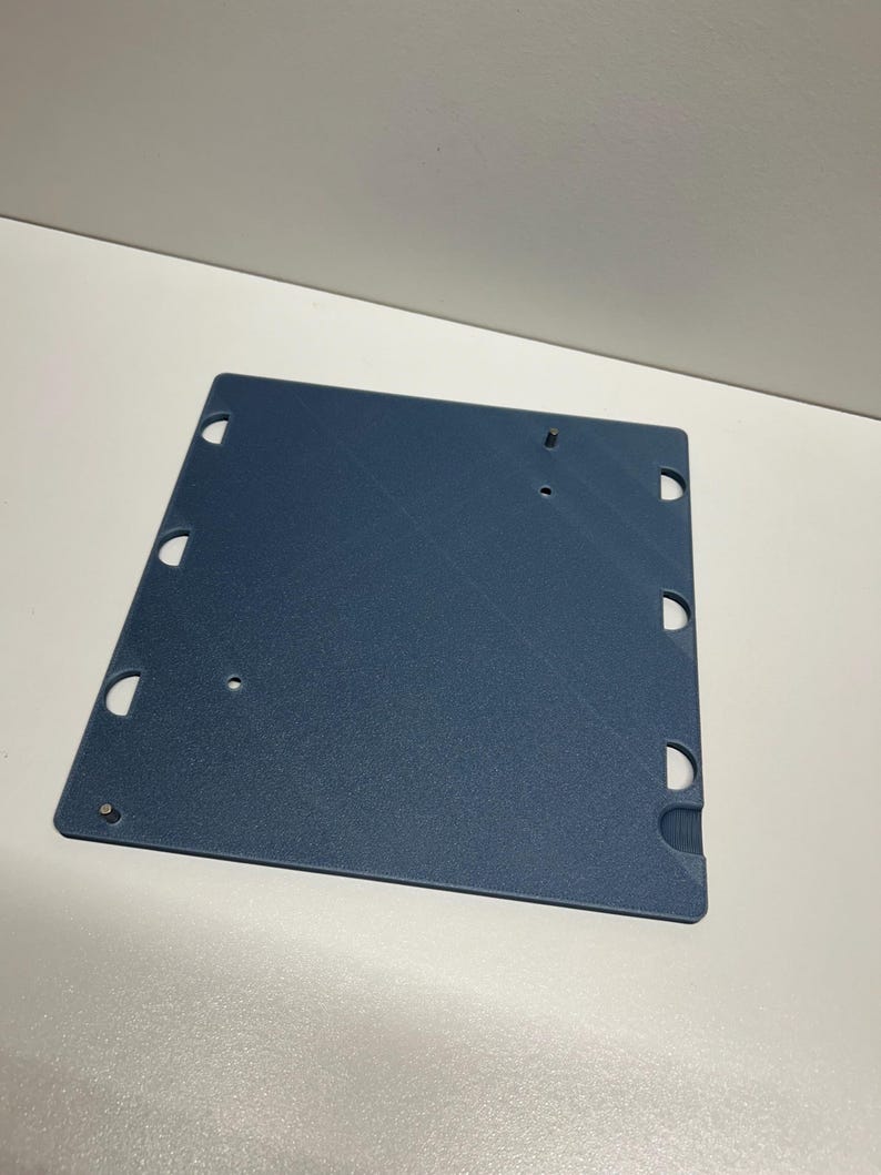 May include: A blue plastic sheet with multiple holes around the edges. The sheet is textured and has a slightly rough surface.