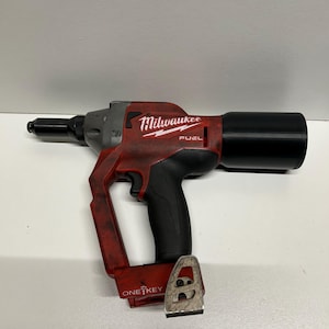 May include: A red and black Milwaukee FUEL cordless rivet gun with a black barrel and a silver ONE-KEY attachment.