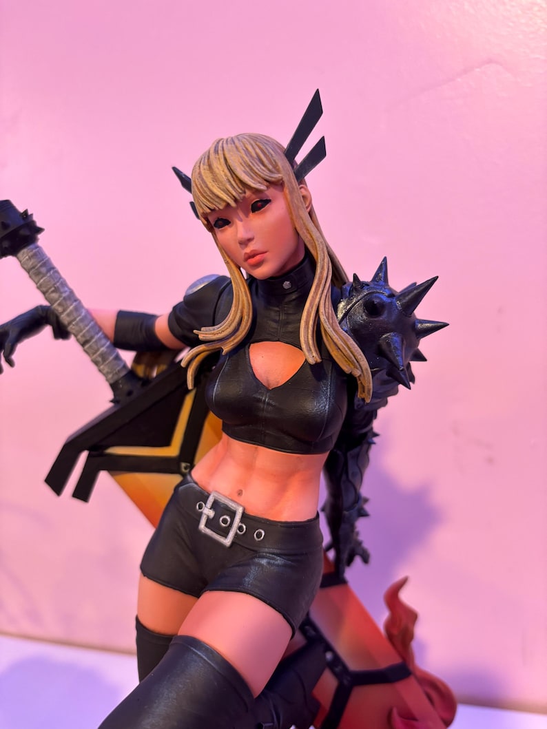 May include: A detailed figurine of a female character with blonde hair, wearing a black outfit with spiked shoulder armor and holding a black guitar. The figure has a determined expression and is posed dynamically.