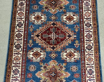May include: A blue and red patterned rug with a geometric design. The rug has a cream border with intricate details.