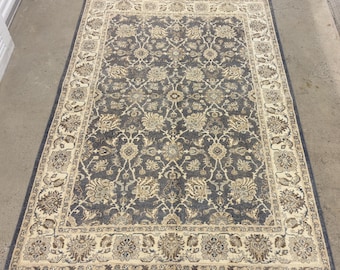 Puede incluir: Una alfombra grande y rectangular con fondo azul oscuro y un patrón floral de color crema. La alfombra tiene un borde con un diseño floral más intrincado.