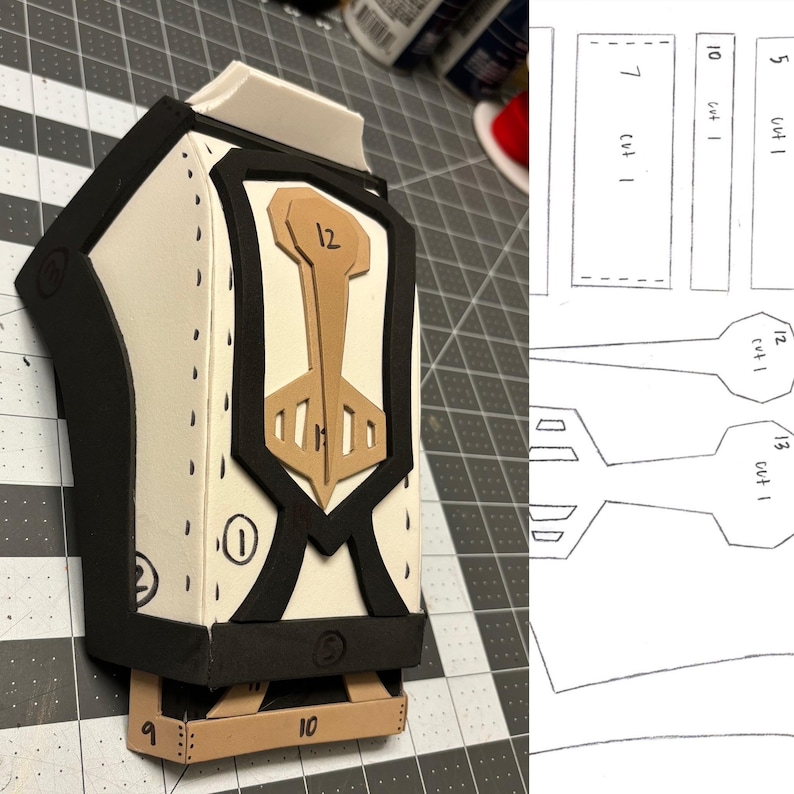 May include: A close-up of a white, black, and brown foam costume piece with numbers 1, 2, 3, 9, 10, 12, and a symbol. The piece is on a black and white grid surface. A diagram of the piece is shown on the right side of the image.