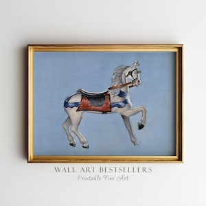 Może przedstawiać: Oprawiony wydruk konia z karuzeli. Koń jest biały z niebieskimi i czerwonymi akcentami, czarnym siodłem i brązową uzdą. Tło jest jasnoniebieskie. Rama jest złota. Tekst na dole: "WALL ART BESTSELLERS Printable Fine Art."
