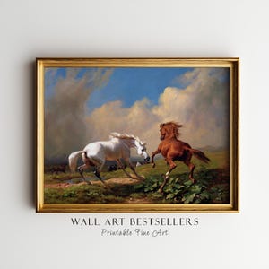 May include: A framed painting depicts two horses in a field. One is white, the other is brown, both in motion. The background features a blue sky with clouds and green foliage. The frame is gold.