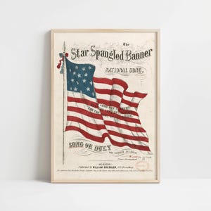 Może przedstawiać: Oprawiony wydruk pieśni narodowej "The Star Spangled Banner". Grafika przedstawia zabytkową ilustrację amerykańskiej flagi z czerwono-białymi pasami i niebieskim polem gwiazd. Wydruk zawiera tekst i jest w drewnianej ramie.