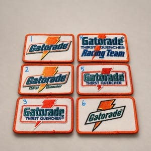 May include: Six rectangular embroidered patches featuring the Gatorade logo and text. Each patch has a white background with an orange lightning bolt graphic and orange borders. The patches are numbered one through six in blue ink.