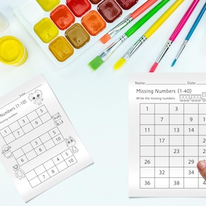 Può includere: Due fogli di lavoro con il testo "Numeri mancanti" e un set di acquerelli e pennelli. Un foglio di lavoro ha i numeri 1-10 e l'altro ha i numeri 1-40. I fogli di lavoro sono per i bambini per esercitare le loro abilità matematiche.