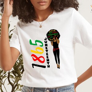 May include: White t-shirt with a black silhouette of a woman with an afro. The afro has the words "freedom, true freedom, independence, equality, Juneteenth" written on it. The year "1865" is written in yellow, red, and green on the left side of the shirt.