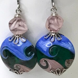 Può includere: Un paio di orecchini pendenti con perle di vetro rotonde e multicolori con motivi a vortice blu, verde scuro e rosa chiaro. Ogni orecchino è decorato con una piccola perla rosa chiaro sfaccettata e coperture in metallo color argento.