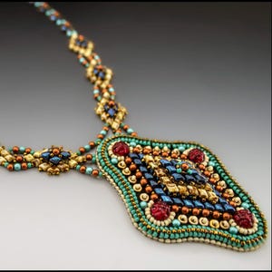 May include: Close-up of a beaded necklace with a pendant. The necklace features gold, teal, navy blue, and red beads. The pendant is a large, ornate shape with a central design and red accents. The necklace is on a gradient background.
