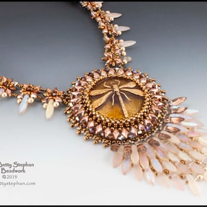 May include: A delicate gold and white beaded necklace with a dragonfly pendant. The dragonfly is encased in a clear resin and has brown wings. The necklace is made with a variety of beads, including seed beads, pearls, and crystals.