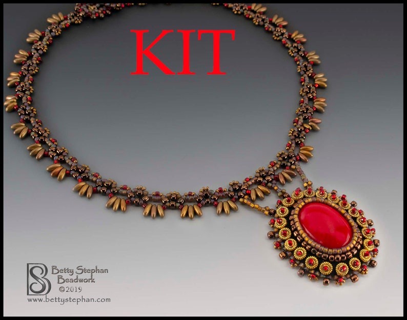 K&ouml;nnte beinhalten: Ein Perlenketten-Set mit einem roten Edelstein-Anh&auml;nger. Die Kette hat eine gold-braune Farbgebung mit einem sich wiederholenden Perlenmuster.