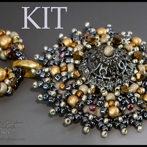 Può includere: Un kit per collana di perline con un ciondolo argentato e dorato che presenta un design circolare con un centro rialzato. Il ciondolo è circondato da una varietà di perline in argento, oro e bianco.