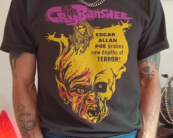 May include: A black t-shirt with a graphic print of a woman with long hair and a monster with a large mouth. The text on the shirt reads "Of the Cry Banshee Edgar Allan Poe probes new depths of TERROR!"