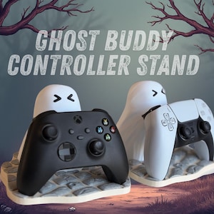 May include: A controller stand shaped like a ghost, holding a black Xbox controller and a white PlayStation controller. The stand has the text "GHOST BUDDY CONTROLLER STAND" above it. The background features a spooky forest scene.