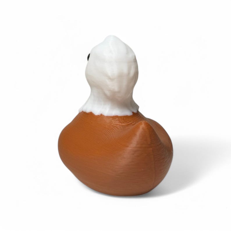 May include: A brown rubber duck with a white head. The duck is facing away from the camera.