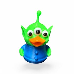 May include: A green three-eyed alien with a bright orange beak wearing a blue shirt. The alien has a green antenna on top of its head.