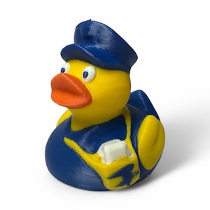 May include: A yellow rubber duck wearing a blue police officer's uniform and hat. The duck has an orange beak and white accents on the uniform. The toy is a novelty item.