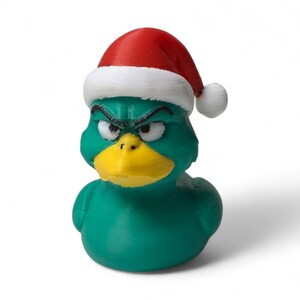 May include: A teal rubber duck wearing a red and white Santa hat. The duck has an angry expression with furrowed eyebrows and a yellow beak. The duck is a novelty item, perfect for Christmas.