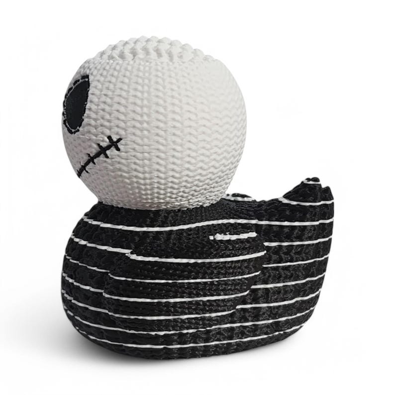 May include: Black and white striped rubber duck with a stitched white face and one black eye.