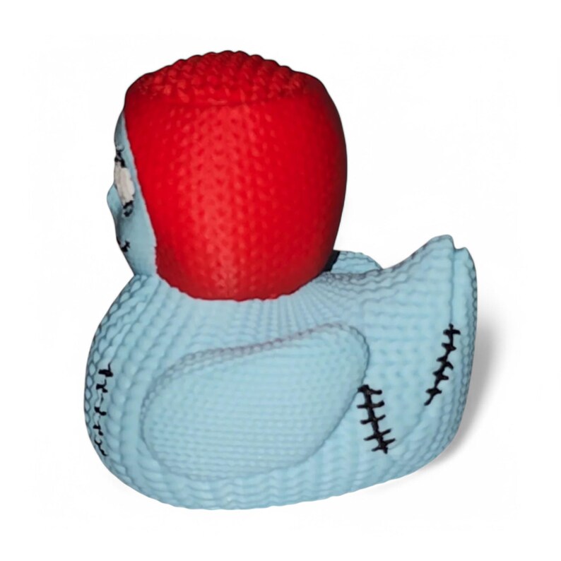 May include: A blue rubber duck with a red knitted hat and black stitching. The duck has a stitched-on smile and eyes.