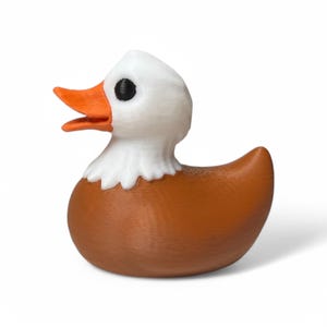 May include: A brown and white rubber duck with a bald eagle design. The duck has a white head with a black eye and an orange beak. The body of the duck is brown with white feathers around the neck.