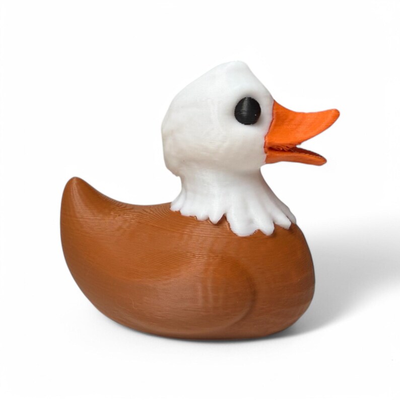May include: A brown and white rubber duck with a bald eagle design. The duck has a white head with a black eye and an orange beak. The body of the duck is brown.