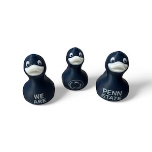 May include: Three blue rubber duck figurines with white details. One duck says "We Are", another says "Penn State", and the third has a Penn State Nittany Lion logo.