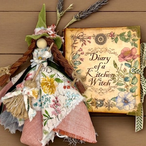 May include: A whimsical witch doll with a green hat and floral dress, next to a vintage-style book. The book cover reads "Diary of a Kitchen Witch" surrounded by floral illustrations. Dried lavender sprigs add a rustic touch.