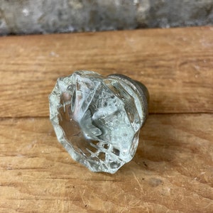 May include: A clear glass door knob with a faceted design. The knob has a silver metal base.