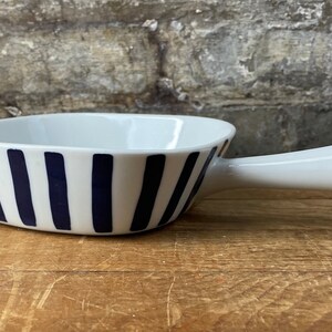 May include: White ceramic serving dish with a blue and white striped design and a single handle.