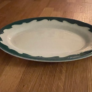 May include: A white oval serving platter with a green scalloped edge.